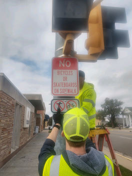 Crew installing "no bikes/skateboards" sign