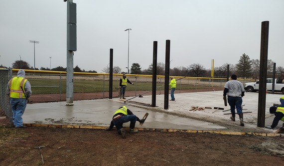 Staff finishing concrete for batting cages
