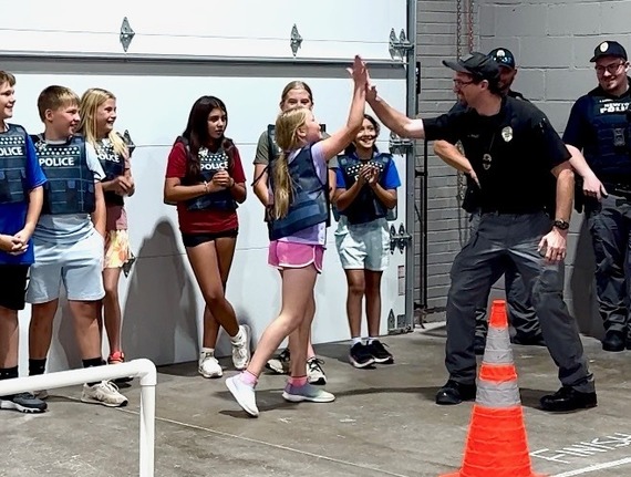 Officer high-fives a kid at NRC Community Camp