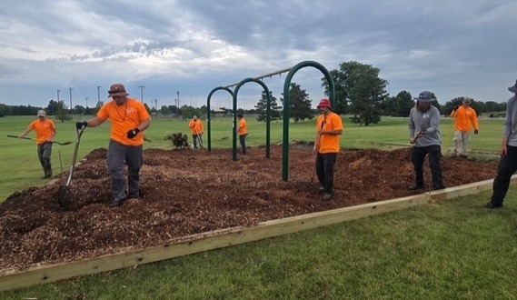 Parks staff spreading mulch for new swing set