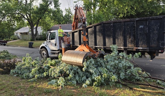 City employee picks up large tree limb with grapple truck