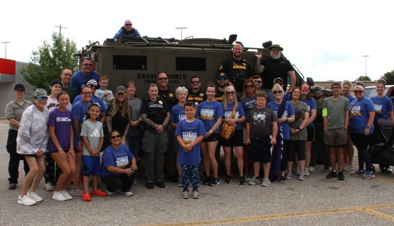 Law enforcement officers, supporters, and friends gather in front of the armored vehicle before the Torch Run