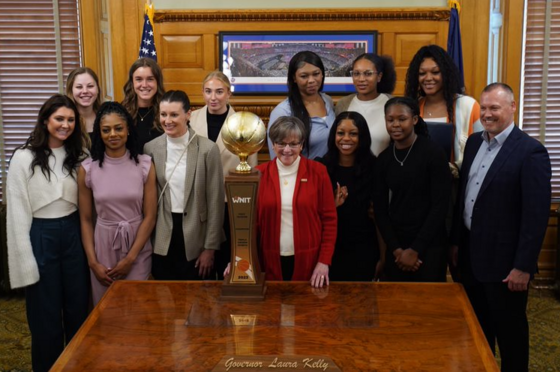 Governor Kelly and the Kansas Women's Basketball team with the National Invitational Tournament championship trophy