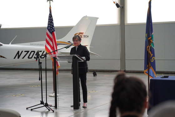 Governor Kelly speaks to a crowd in front of an airplane