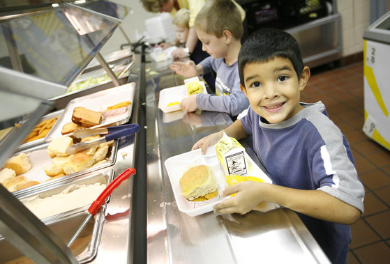 A picture of a boy with a school lunch in a cafeteria line.