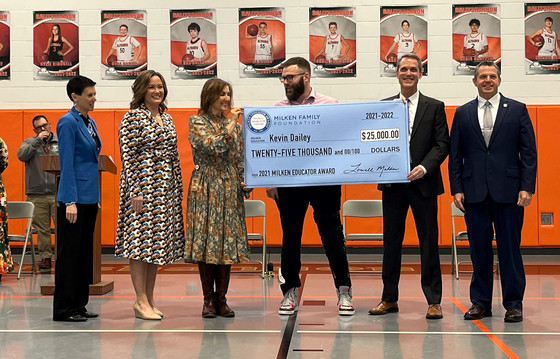 Picture of six people standing in a gym with a large ceremonial check made out to Kevin Dailey for $25,000.