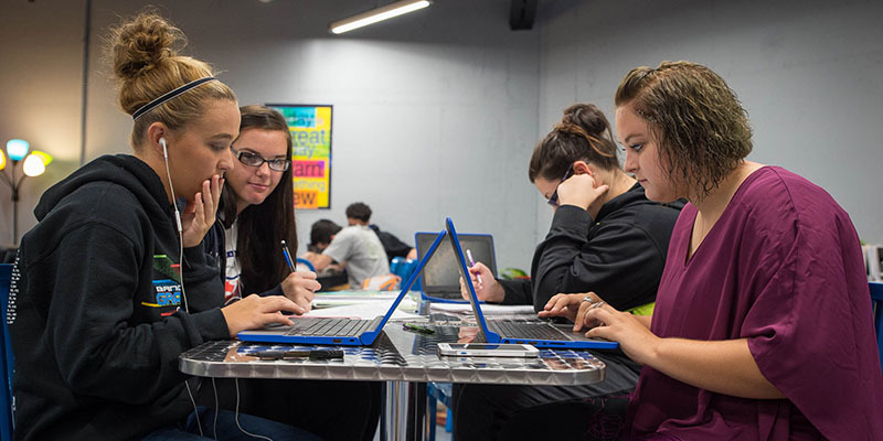 Picture of a group of four young women working on computers at a table.
