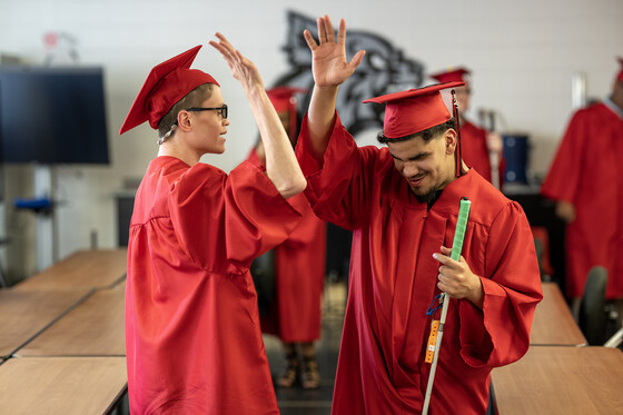 Two male Kentucky School for the Blind graduates high five each other before receiving their diplomas