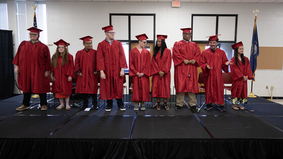 Nine graduates of the Kentucky School for the Blind stand smiling in their caps and gowns