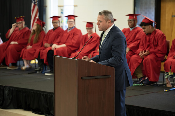 Jason E. Glass speaks at a podium while Kentucky School for the Blind graduates sit behind him 