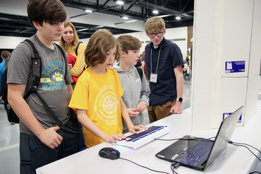 A group of students huddle around a laptop