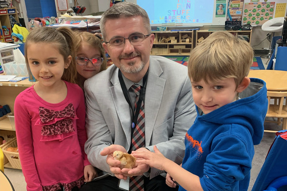 Robbie Fletcher poses for a photo with three children and some baby chickens in his hand