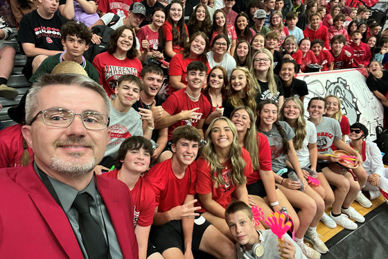 Robbie Fletcher takes a selfie with a gymnasium full of students