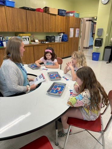 Teacher at kidney table with students working with letter trays