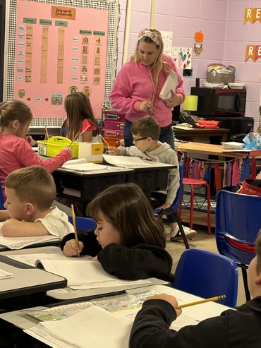 Teacher working with students as they are writing