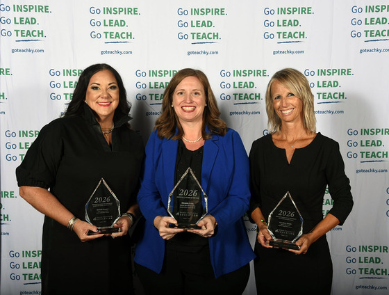 Melanie Howard, Michelle Gross and Kara Byrn Dowdy smile together while holding glass trophies.