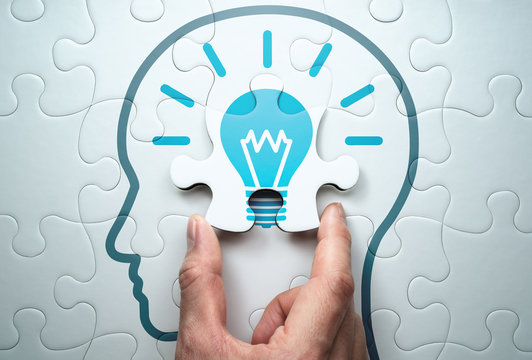 Graphic of a puzzle of a human head, with a hand inserting a puzzle piece with a lightbulb on it in the middle of the head.