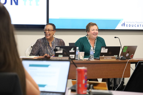Sharon Porter Robinson and Lu Young laugh while talking and sitting at a desk