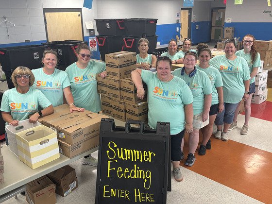 Smiling members of the Owen County summer meals program stand by boxes of food to be given out to children.