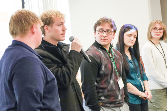 Students standing in front of a crowd holding a microphone