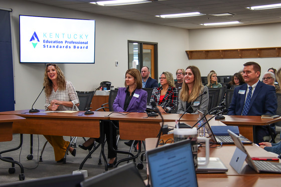 group of individuals sit at a table addressing a panel of people