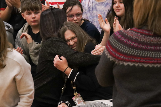 Two people hug in a crowd of others on bleachers