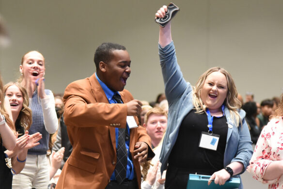 A woman holds a fist up in celebration while a man next to her cheers along