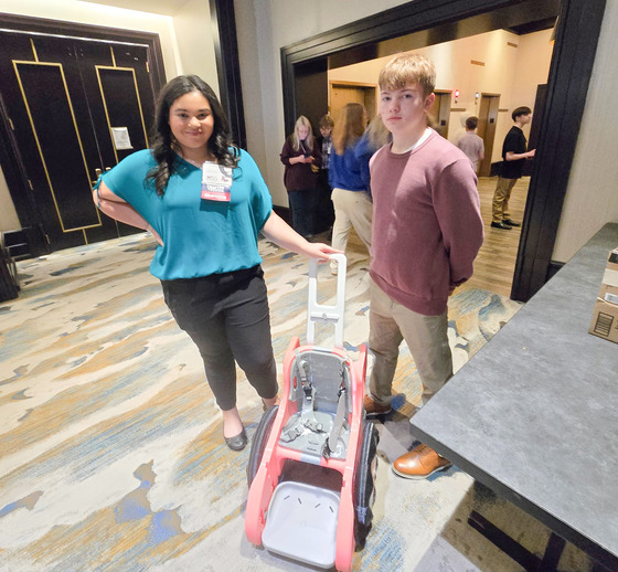 Students stand behind a 3D printed wheelchair 