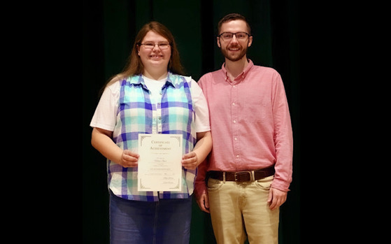 Tyler Saylor stands next to senior Haley Jones, who holds up a certificate.