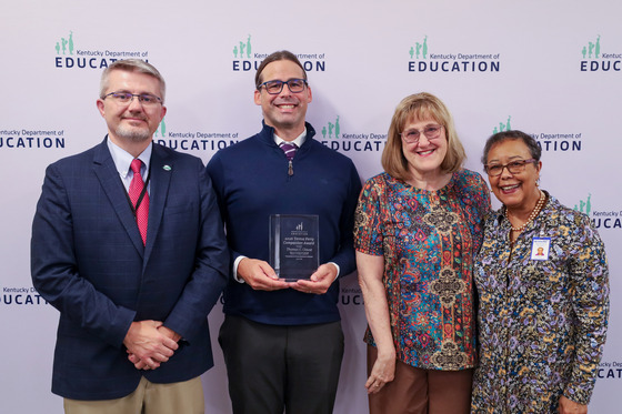 Four people standing in front of a background accepting an award