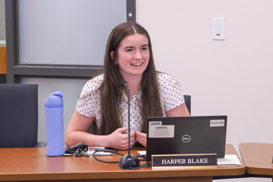 A female smiles while sitting at a table.