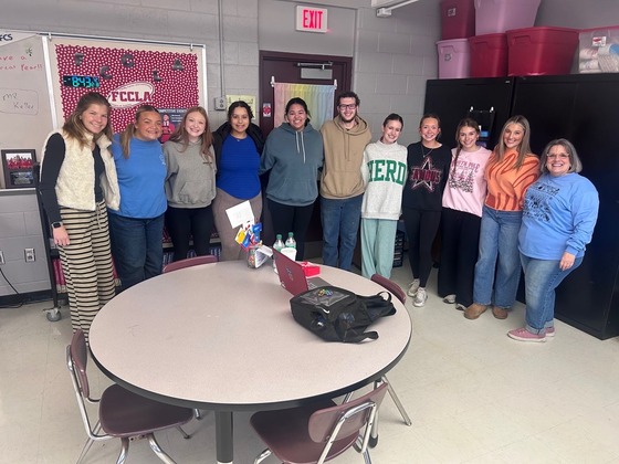 A teacher and students stand in a half circle posing for a picture