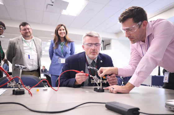 Commissioner Robbie Fletcher using a soldering iron to solder a wire on an LED light.