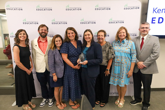 Group of people accepting an award on a white background