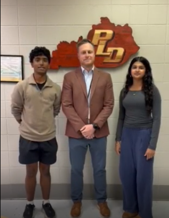 Picture of two students standing on either side of their principal.