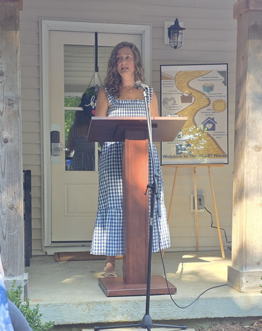 Tiffany Reynolds standing on a porch and speaking at the opening of the HEART House in Bullitt County.
