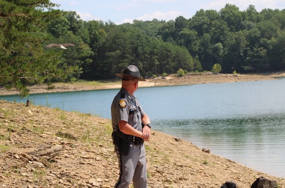 A Trooper in uniform looking back at a bald eagle flying over a lake.