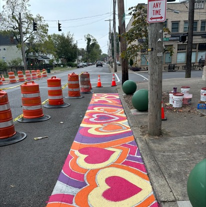 Photo: Intersection of dumesnil and 28th, orange yellow and purple floral street art is on the crosswalks