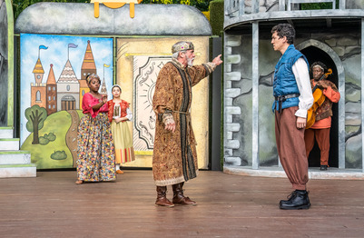 Actors from the kentucky shakespeare organization. Two women and three men stand acting on a stage in costume acting with a painted castle background