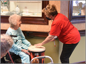 Cora Hughes helps a resident learn drumming at Wesley Village.