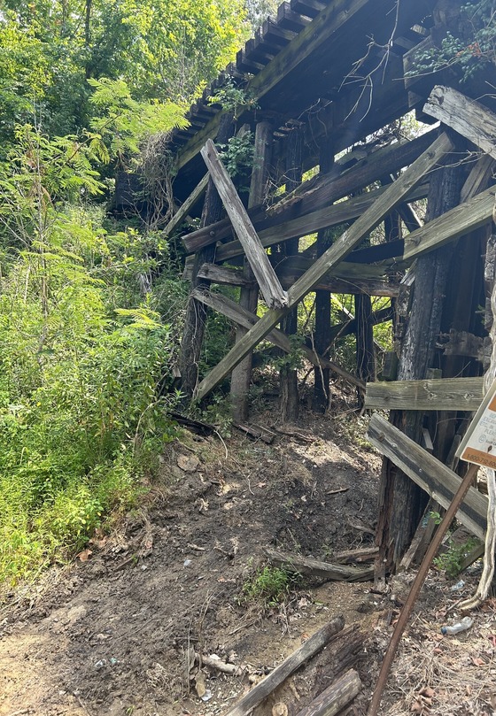 Damaged to the abandoned railroad bridge caused by a recent crash is visible.