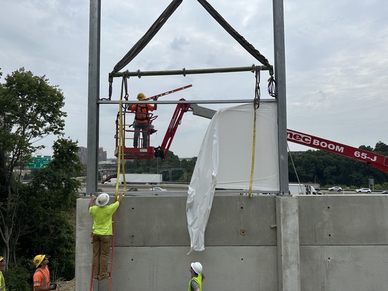 First noise screening barrier installed in state of Kentucky. Construction workers slide panel into place.
