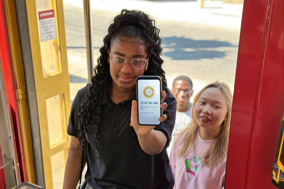 Teenagers using Opportunity Pass on phone to board streetcar.