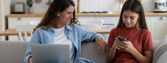 Mother and daughter on the sofa, on their laptops and phones