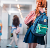 Student with a backpack on looking down a school hallway
