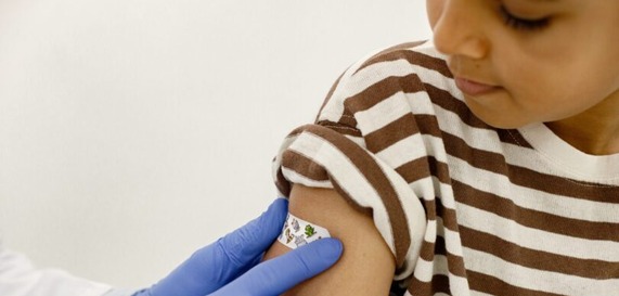 Doctor putting a band-aid on a child's arm after receiving a vaccine