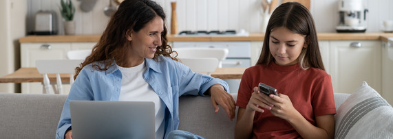 Mother and teen daughter on mobile devices on the couch