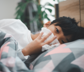 Sick child lies in bed with tissue