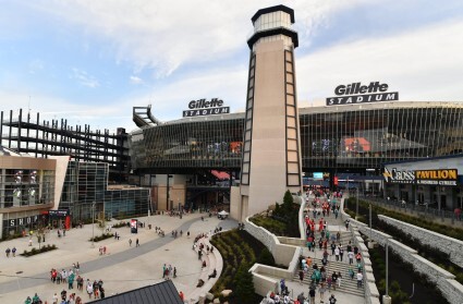 gillette stadium from the outside with lots of people walking on the stairs and in the open plaza area