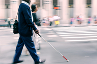 Man using white cane while walking down street